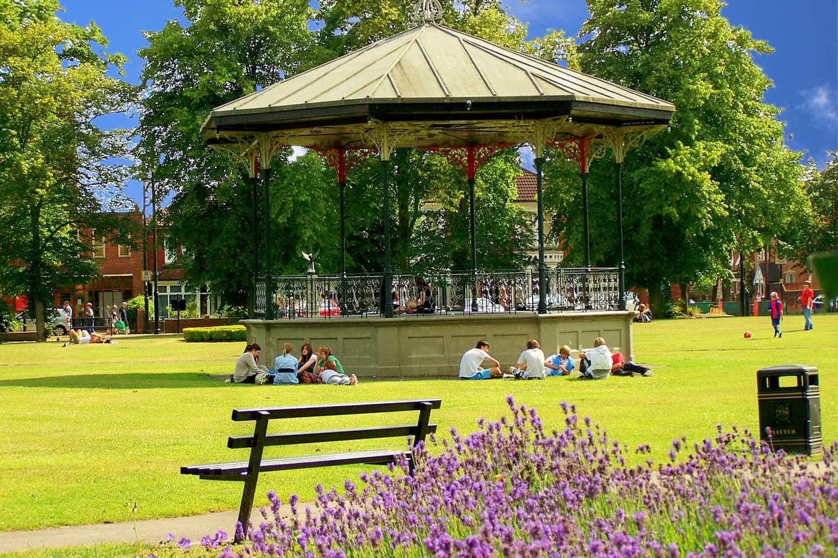 The Victorian bandstand in Eastleigh Park with people relaxing on the grass
