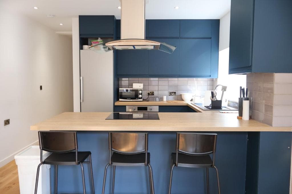 Kitchen with blue cabinets and a breakfast bar with stools